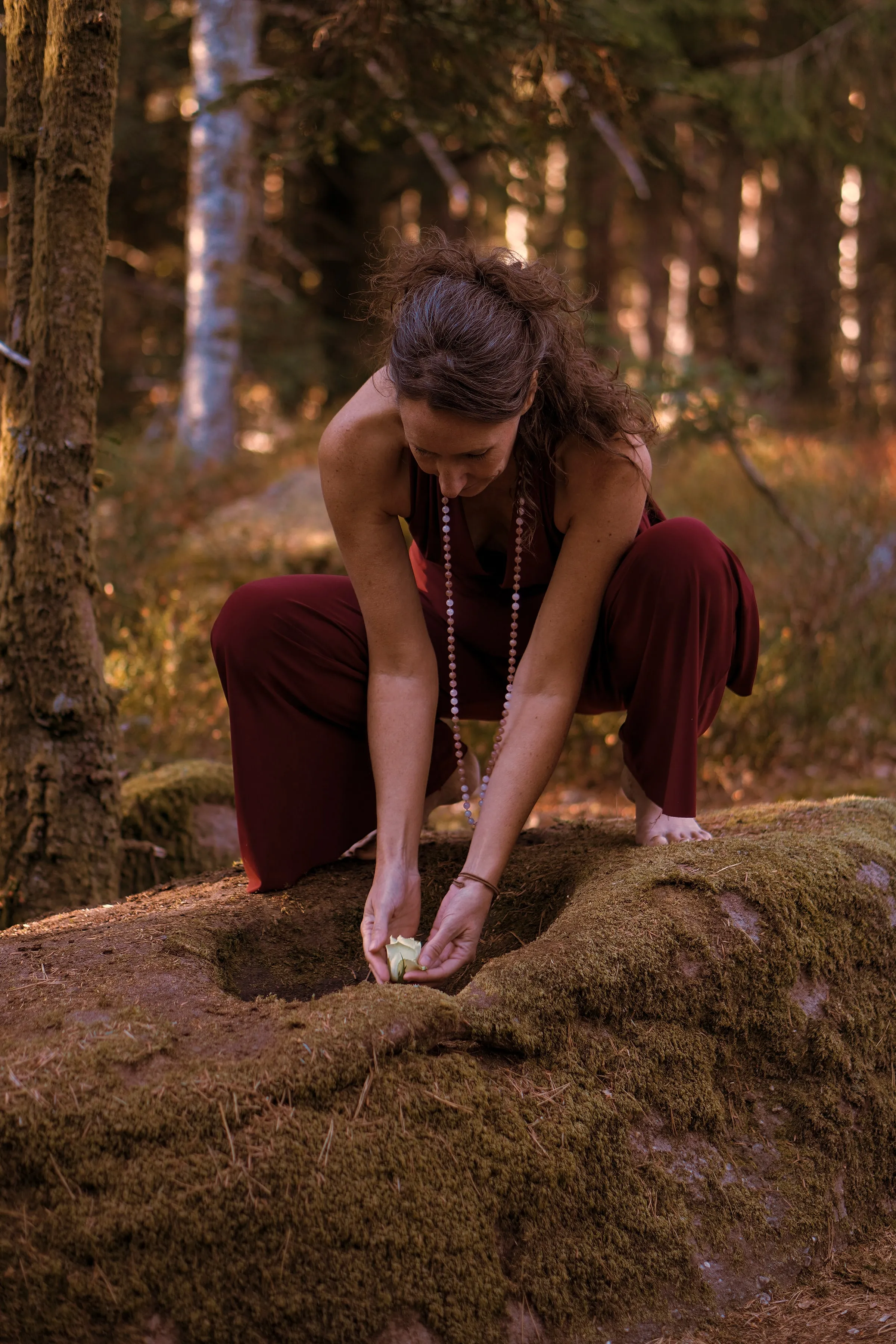 Johanna Schütte hockt auf einem moosigen Felsen und hält einen Stein